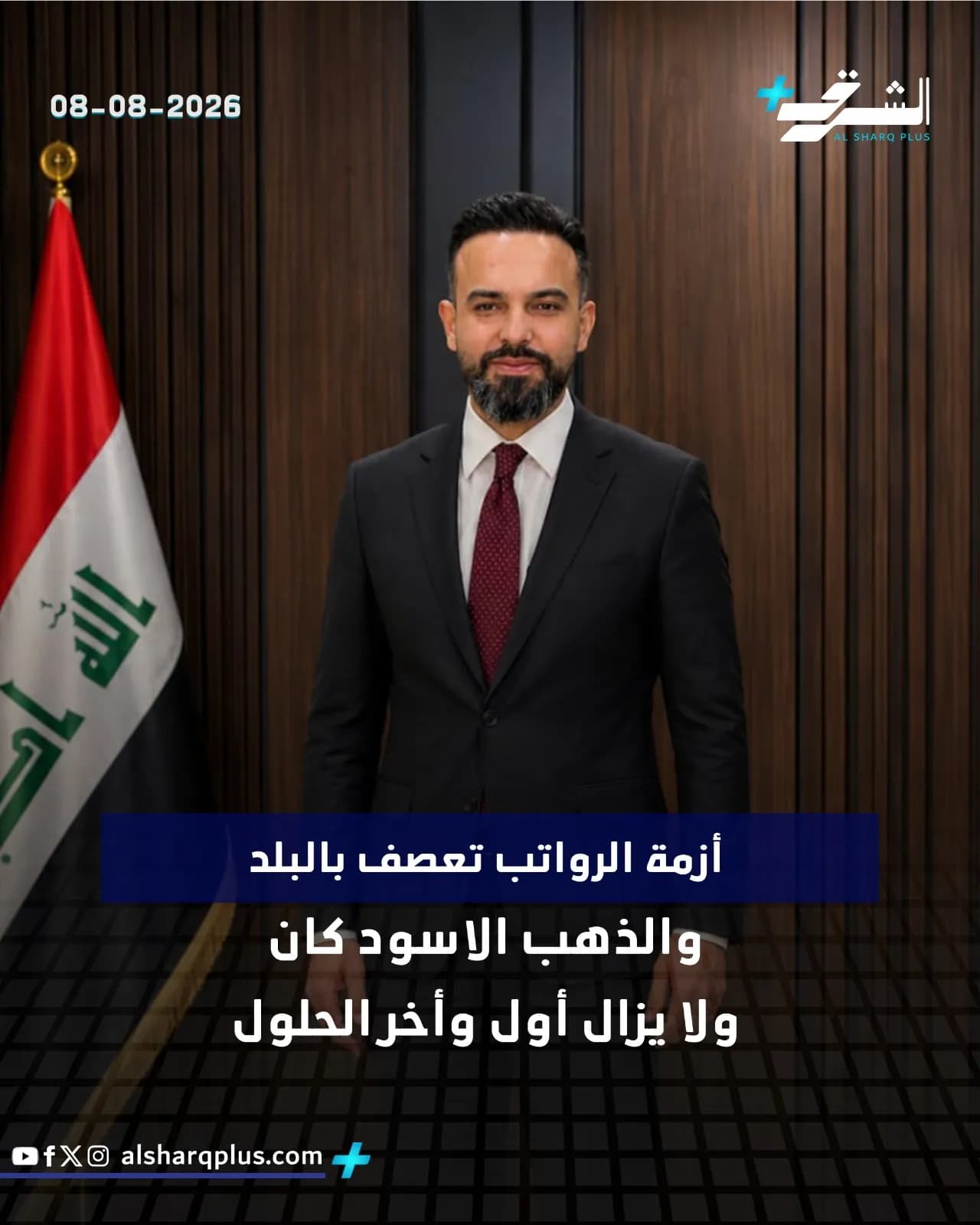 رجل يرتدي بدلة سوداء وربطة عنق حمراء يقف أمام جدار خشبي، مع علم عراقي على يساره وشعار قناة الشرق أعلى اليمين.