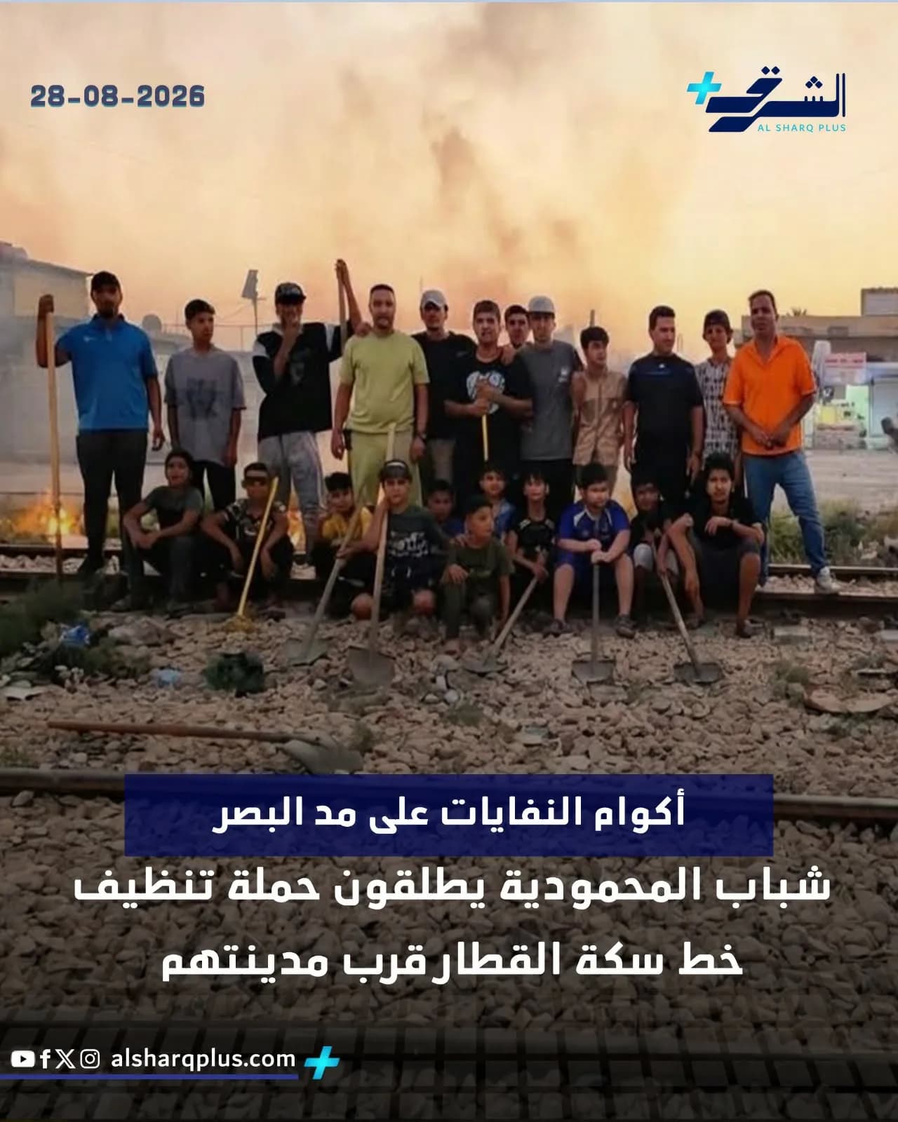 شباب وفتيان يحملون أدوات تنظيف يقفون على خط سكة حديد عليه أكوام نفايات.
