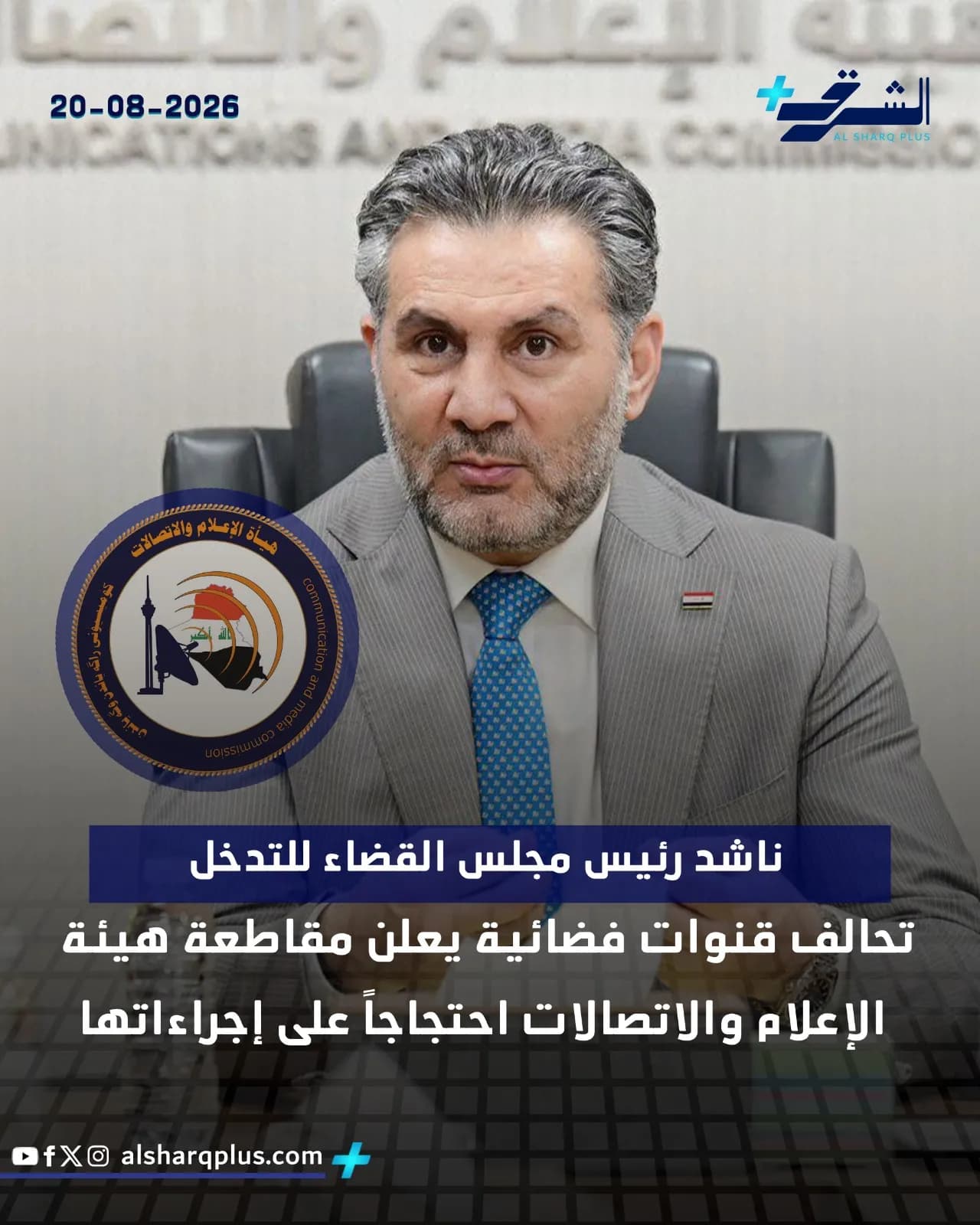 رجل أصلع ملتح يرتدي بدلة رسمية وربطة عنق زرقاء منقطة، يجلس وينظر مباشرة إلى الكاميرا.