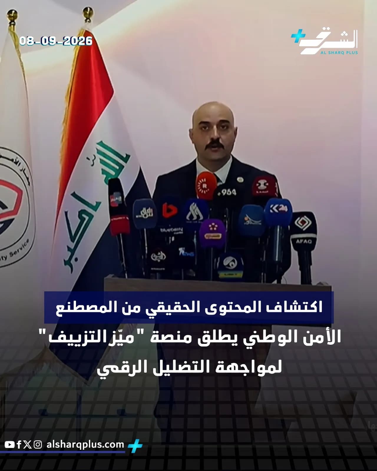 رجل أصلع بلحية يرتدي بدلة داكنة يتحدث خلف منبر ميكروفونات، وبجانبه أعلام عراقية وعربية.