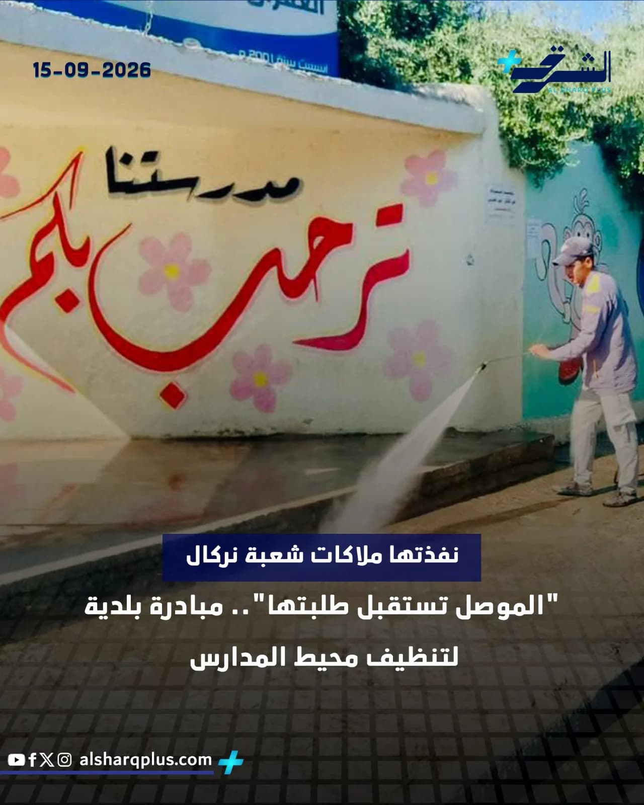 رجل يرش الماء على جدار مدرسة كجزء من حملة تنظيف، وعلى الجدار كتابة عربية ترحيبية.