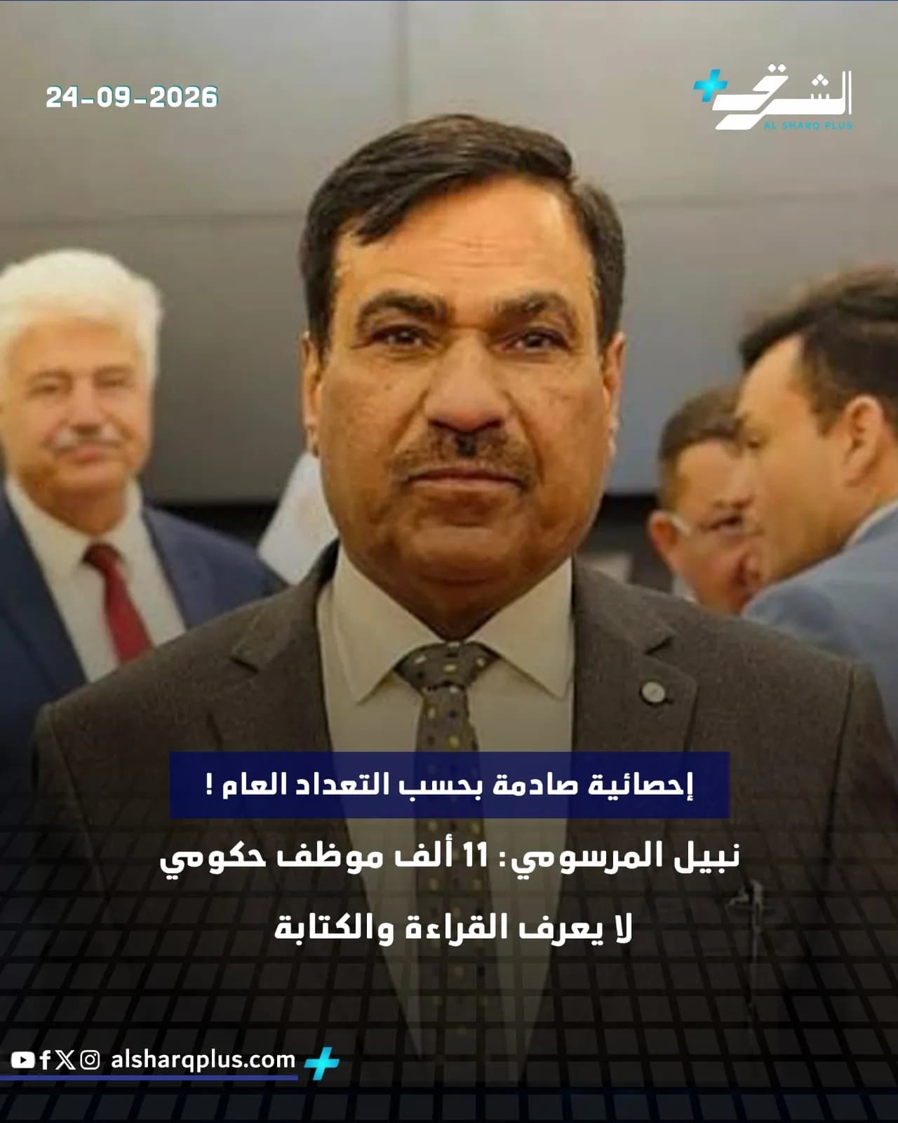 رجل يرتدي بدلة داكنة وربطة عنق منقطة ينظر إلى الأمام مباشرة، وإلى يساره رجل أشقر وآخران في الخلفية.