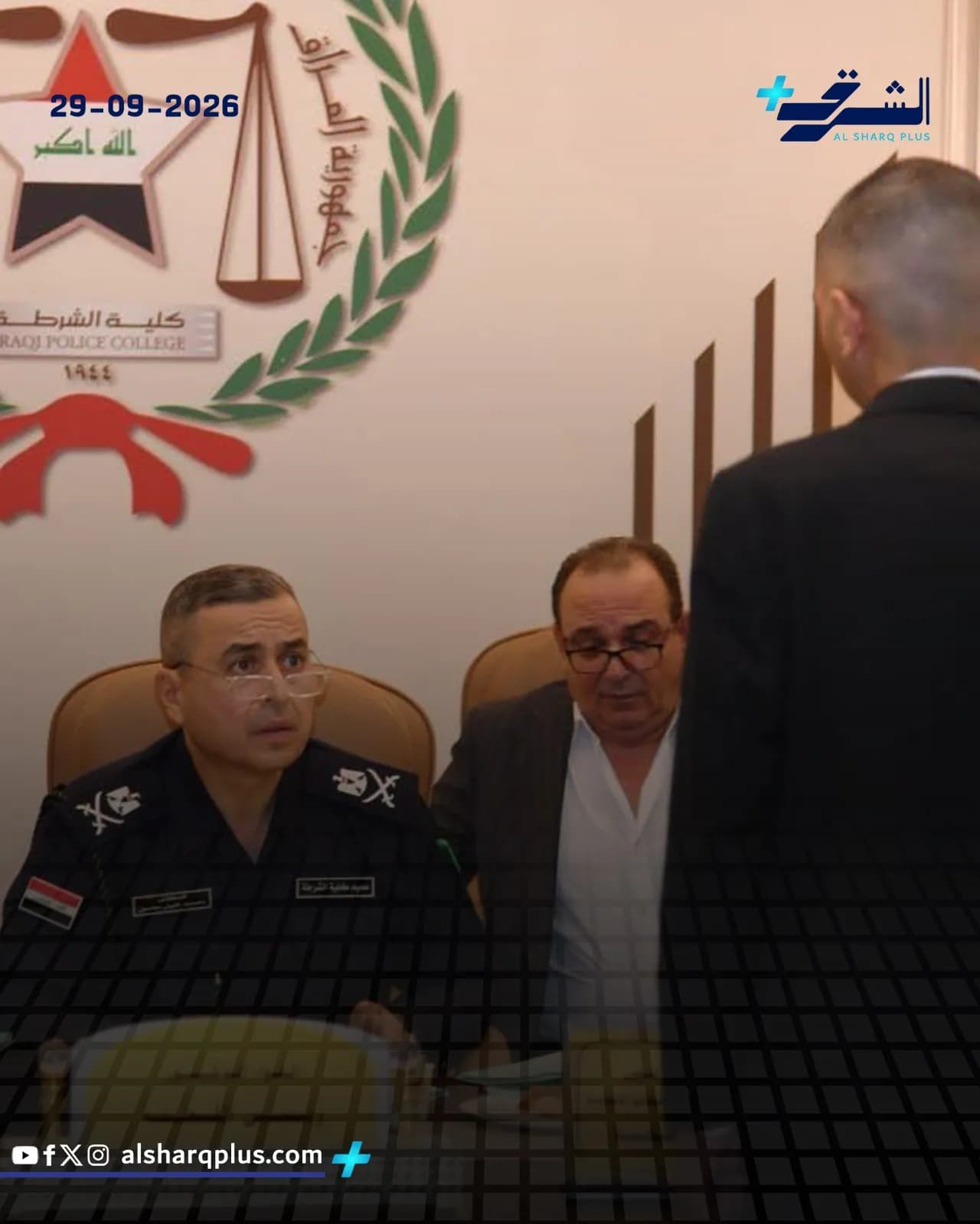 ضابط شرطة عراقي يرتدي نظارة يجلس إلى طاولة اجتماعات مع رجل آخر أثناء فعالية.