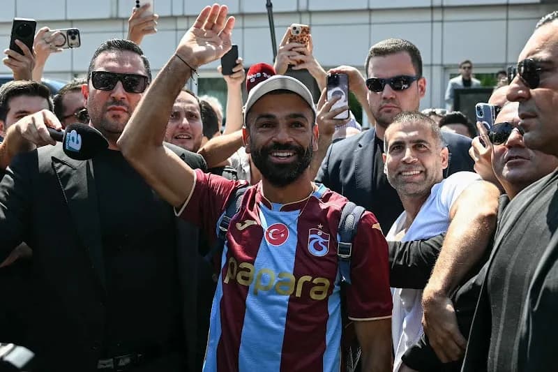 محمد صلاح يبتسم ويرفع يده بين حشد من المشجعين وبعضهم يلتقط الصور.