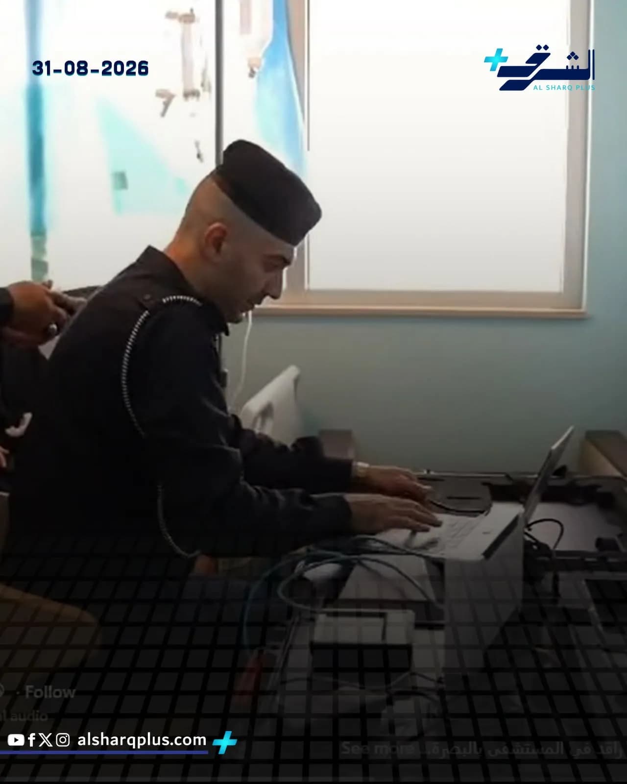 ضابط شرطة حليق الرأس يرتدي زيًا أسود وقبعة سوداء ويستخدم حاسوبًا محمولًا على مكتب.